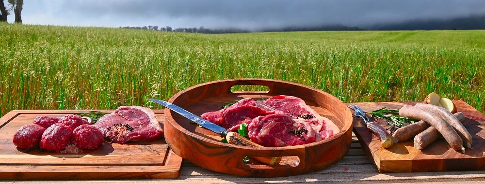 Beef produce displayed in front of farm landscape