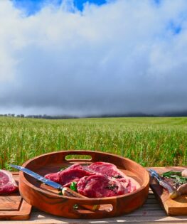 Beef produce displayed in front of farm landscape